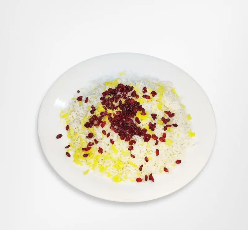 یک بشقاب زیبای برنج زعفرانی و سفید مخلوط شده با زرشک‌های ترش و قرمز، غذای سنتی و لذیذ از منوی ویژه رستوران امینی.