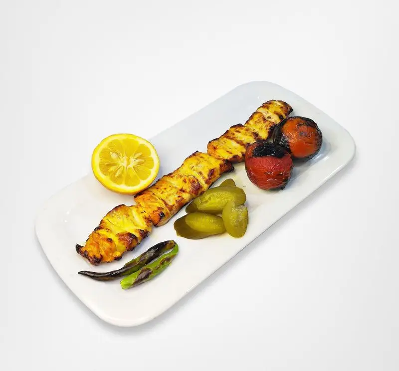 جوجه کباب زعفرانی رستوران امینی، یک غذای سنتی ایرانی با گوجه کبابی، خیارشور تازه، لیمو و فلفل کبابی.