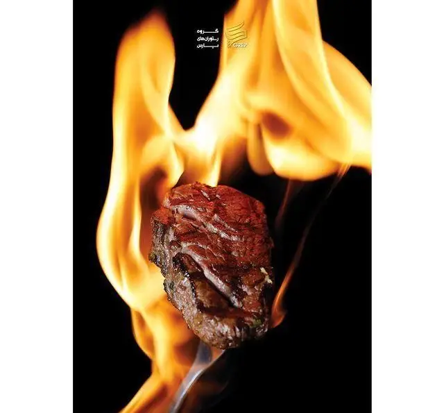تصویر نزدیک از استیک گوشت آبدار گریل شده با شعله‌های رقصان آتش، ارائه دهنده طعم اصیل در کافه رستوران گرپ.