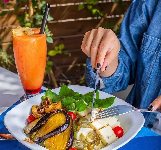 یک بشقاب سالاد و پنیر گریل شده با بادمجان و قارچ در کافه رستوران گرپ، همراه با اسموتی تازه، مناسب برای یک وعده غذایی سالم و خوشمزه.