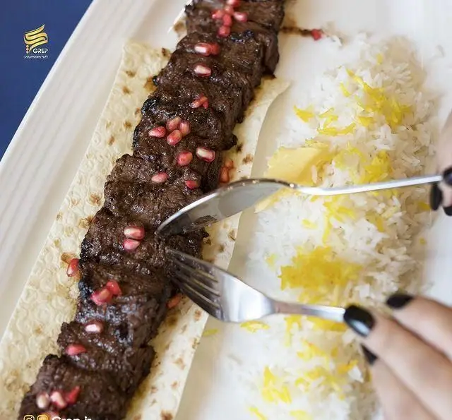 کباب برگ لذیذ کافه رستوران گرپ با تزیین دانه های انار، سرو شده همراه با برنج زعفرانی و کره. تجربه‌ای خوشمزه از غذای ایرانی.