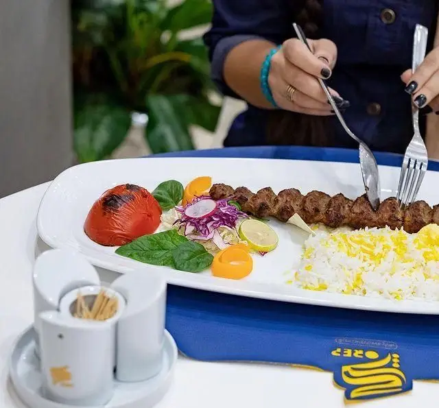 کباب کوبیده با برنج زعفرانی، گوجه کبابی و سالاد در کافه رستوران گرپ. غذای لذیذ ایرانی در محیطی دلنشین برای مشتریان.