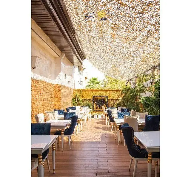 فضای باز کافه رستوران گرپ با میز و صندلی‌های راحت، کفپوش چوبی، دیوار آجری، پوشش گیاهی و سایه بان. محیطی دلنشین و شیک.