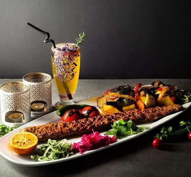 نمای کامل از غذای اصلی کافه رستوران گرپ شامل کباب کوبیده با سبزیجات کبابی، دورچین و نوشیدنی خاص.