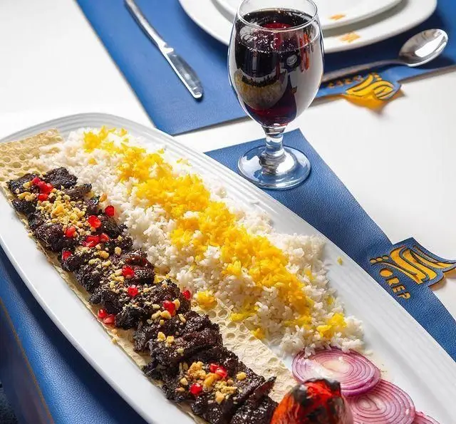 کباب گوشت با تزئین انار و مغز، برنج سفید و زعفرانی، پیاز و گوجه در کافه رستوران گرپ. تجربه غذای اصیل ایرانی.