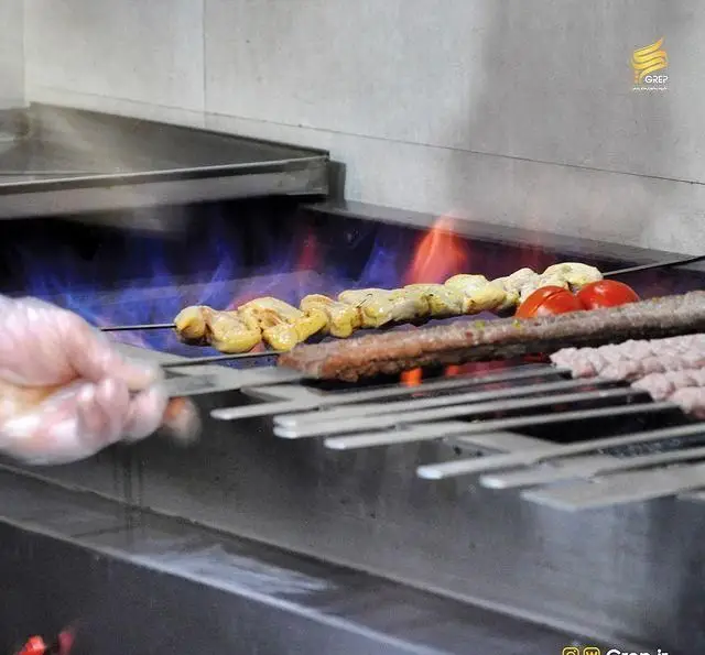 پخت کباب‌های لذیذ ایرانی شامل جوجه و کوبیده تازه بر روی گریل شعله‌ای در کافه رستوران گرپ. تجربه‌ای فراموش‌نشدنی از طعم اصیل.