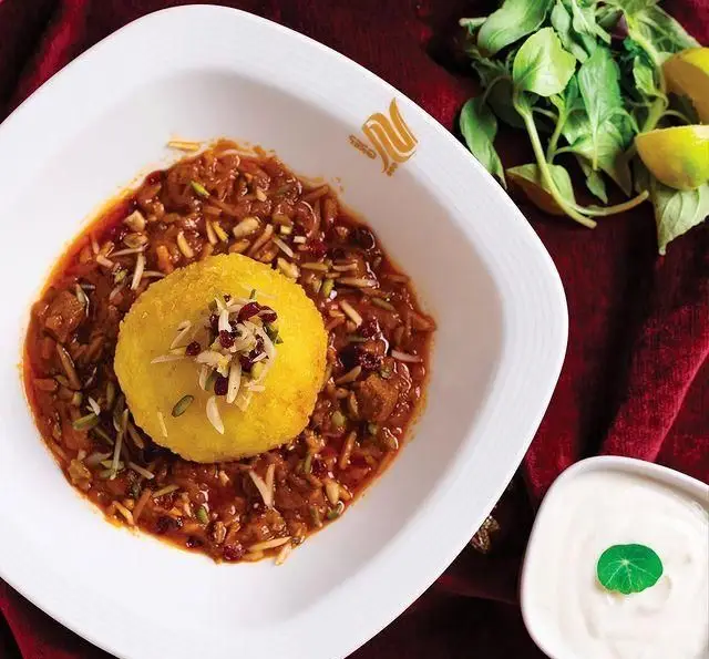 غذای مجلل و سنتی ایرانی در کافه رستوران گرپ: خورش زعفرانی گوشت با برنج قالبی، تزئین شده با زرشک و خلال پسته و بادام.