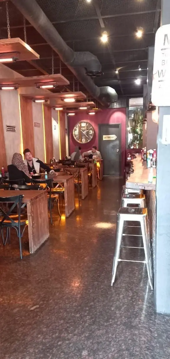 فضای داخلی دلنشین رستوران و کافه میخوش؛ دکوراسیون چوبی مدرن، نورپردازی گرم و محیطی دنج برای مشتریان در حال صرف غذا.