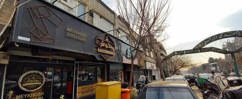 نمای بیرونی و تابلو رستوران میخوش در تهران با شماره 88513280. یک کافه و رستوران مدرن در خیابانی شلوغ.