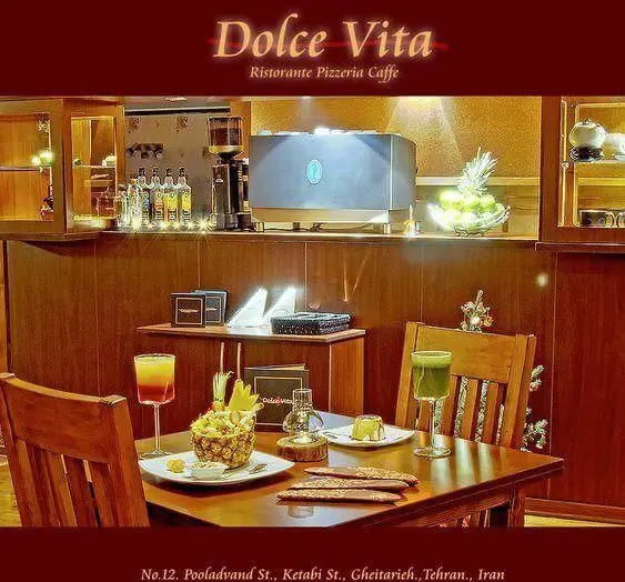 نمای داخلی کافه رستوران ایتالیایی دلچه ویتا در قیطریه تهران، با دکوراسیون گرم و دنج، میزهای چوبی و سرو نوشیدنی و دسر.