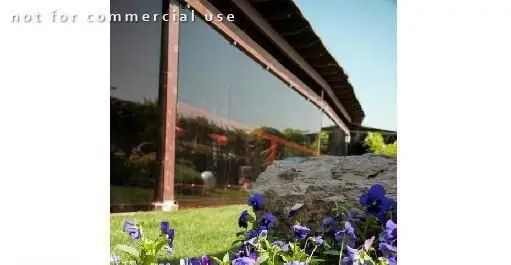 فضای بیرونی سالادبار پامولا با پنجره‌های شیشه‌ای بازتابنده، چمن سرسبز، سنگ و گل‌های بنفش، محیطی دلپذیر برای تجربه غذای سالم.