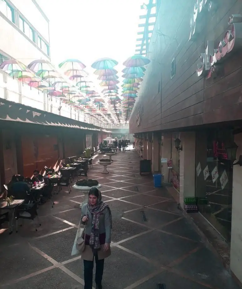 تصویری از فضای دلنشین و باز کافی شاپ دیزی تو، مزین به چترهای رنگی معلق. محیطی دنج برای مشتریان و لحظات فراموش‌نشدنی.