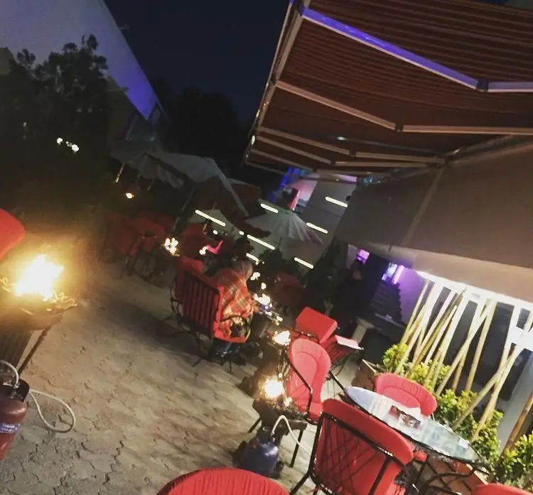 تصویری زیبا از فضای باز و دلنشین کافه رستوران پلاتو در شب، با میز و صندلی‌های قرمز، نورپردازی خاص و آتشدان‌های گرم برای دورهمی‌های دوستانه و شب‌نشینی.