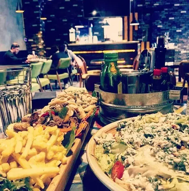 تصویری جذاب از میز غذای کامل در کافه رستوران پلاتو: سیب زمینی سرخ کرده، پاستا، سالاد تازه و نوشیدنی در محیطی دلنشین و مدرن.