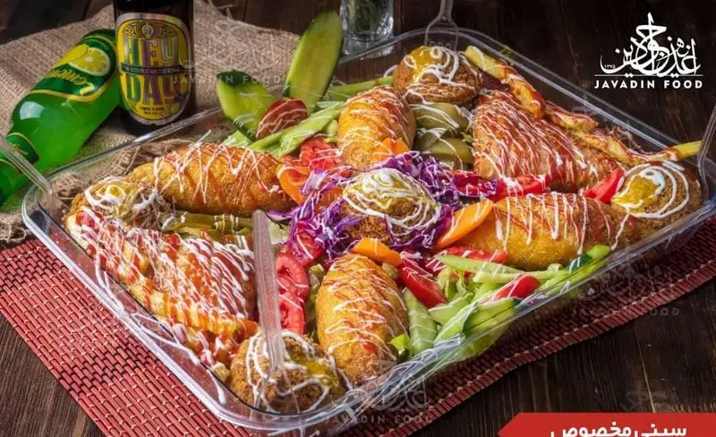 سینی مخصوص و پرطرفدار اغذیه جوادین: مجموعه‌ای از غذاهای سرخ شده خوشمزه، سالاد رنگارنگ، ترشی و نوشیدنی‌های سرد.