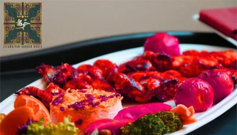 یک بشقاب غذای شیک شامل کباب قرمز، برنج مجلسی و دورچین رنگارنگ در محیط دلنشین رستوران بین المللی خوارزمی.