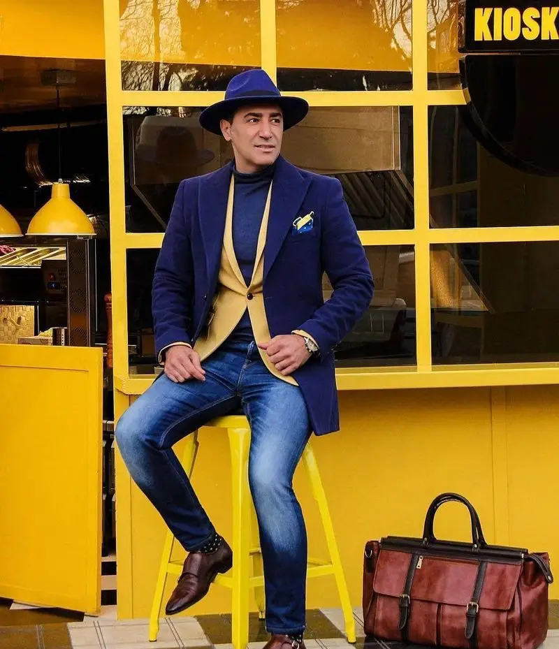 مردی با استایل شیک در کنار دکوراسیون زرد کیوسک برگر، نشان‌دهنده فضای مدرن و جذاب فست‌فود کیوسک برگر.