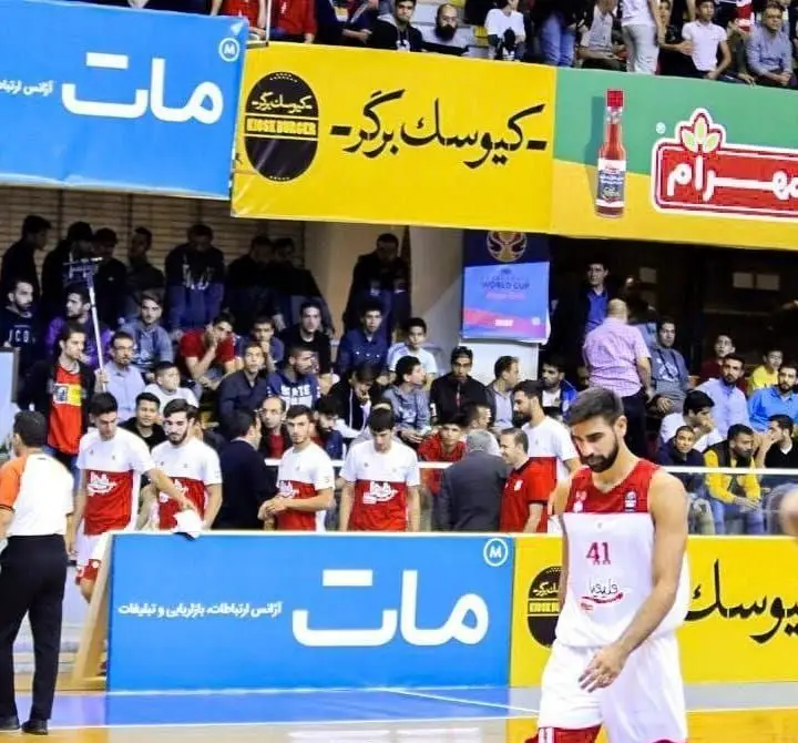 تصویر بیلبورد کیوسک برگر به عنوان اسپانسر در یک مسابقه بسکتبال، نمایشگر تبلیغات موثر این فست‌فود در محیط ورزشی.