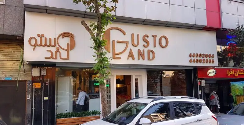 کافه رستوران گاستولند (Gusto Land) با نمای بیرونی شیک، تابلوی بزرگ و شماره تلفن‌های تماس 44002004 و 44002005.