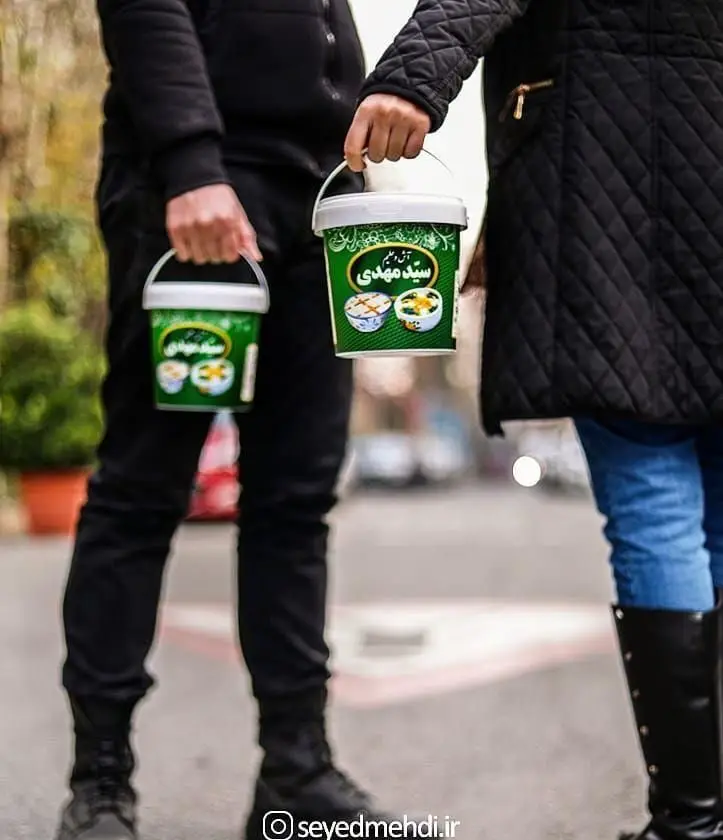 دو نفر در حال حمل سطل‌های سبز رنگ آش و حلیم آماده سید مهدی با کیفیت بالا، مناسب برای نذری و وعده‌های غذایی