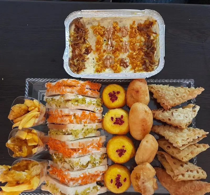 سفارش غذای خونگی مامی فود: سینی مجلسی شامل فینگرفود، کشک بادمجان با تزیین گردو و زرشک، شیرینی‌های متنوع و سیب‌زمینی مخصوص مراسم شما.