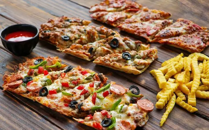 انواع پیتزا فست فود شیلا با سوسیس، زیتون، فلفل دلمه و پنیر روی میز چوبی، به همراه سیب زمینی سرخ کرده و سس.