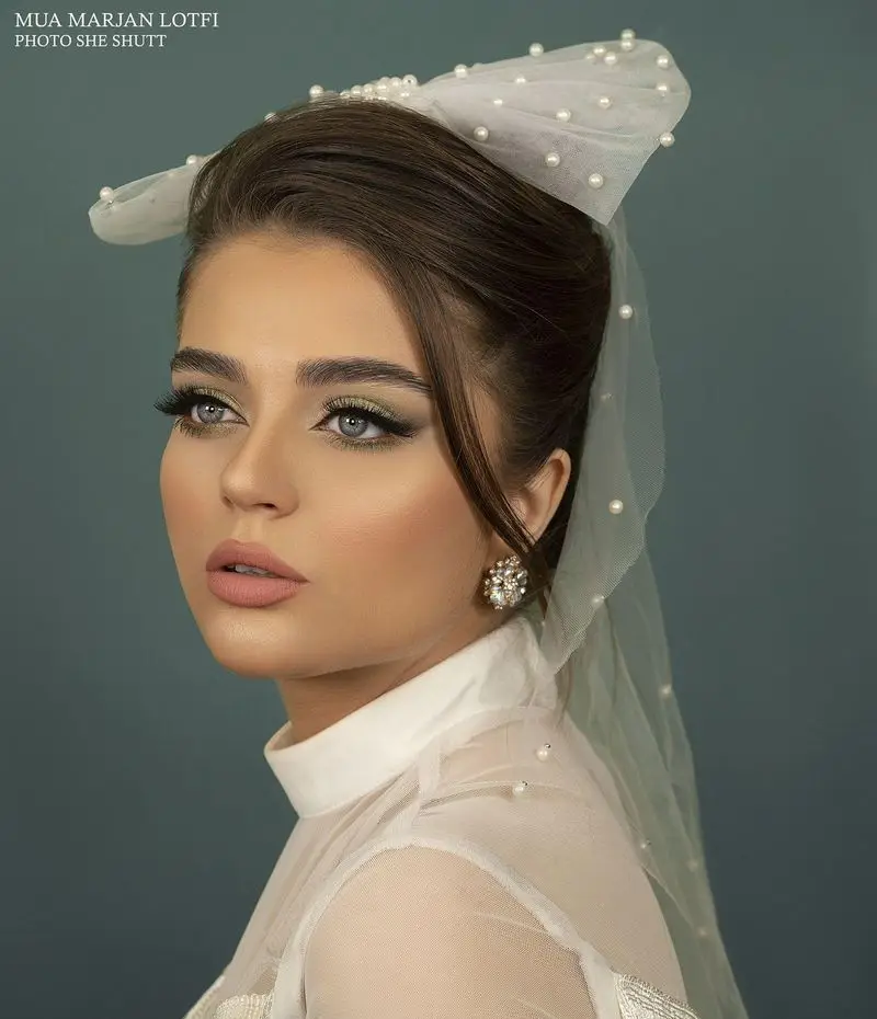 مدل عروس با میکاپ لایت و سایه چشم ملایم، شینیون بسته تزئین شده با تور و مروارید سفید اجرا شده در سالن زیبایی مرجان لطفی.