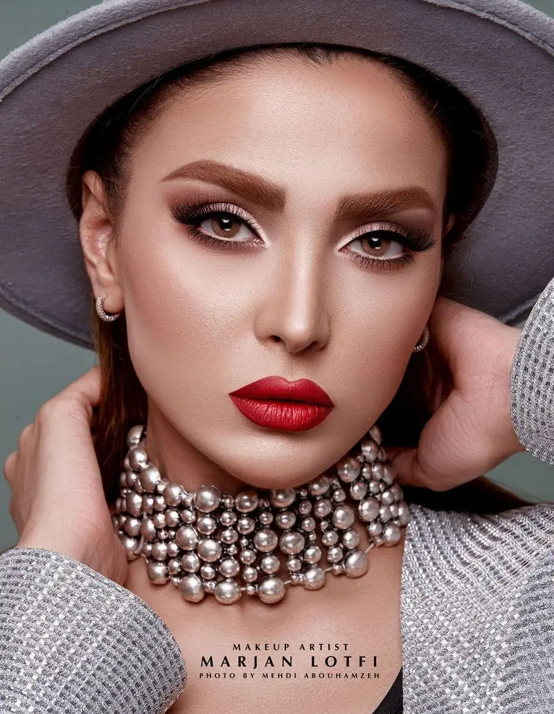 نمای نزدیک از چهره زنی با رژ لب قرمز پررنگ، آرایش چشم دودی و گردنبند مرواریدی نقرهای، نمونه کار میکاپ در سالن زیبایی مرجان لطفی.