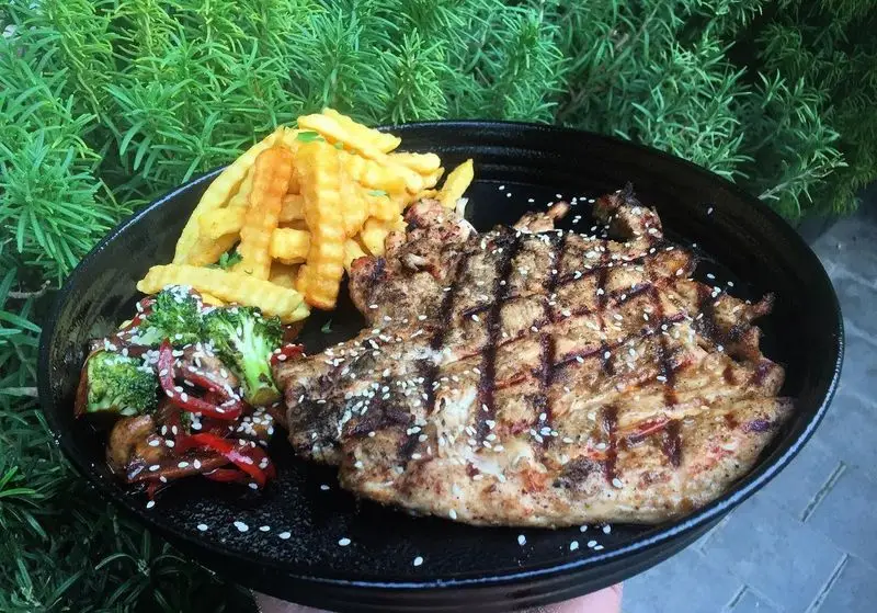 عکس غذای لذیذ رستوران پروفسور: مرغ گریل شده با سس مخصوص، سیب زمینی سرخ کرده و سبزیجات تازه با کنجد.