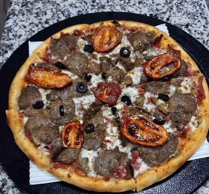 پیتزا گوشت و گوجه تازه و خوشمزه رستوران پروفسور، با تکه‌های آبدار گوشت، گوجه کبابی و زیتون سیاه، بهترین انتخاب برای شام.