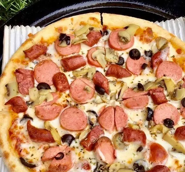 پیتزای خوشمزه رستوران پروفسور شامل سوسیس‌های حلقه‌ای و تکه‌ای، قارچ و زیتون سیاه روی سس سفید و پنیر ذوب شده.