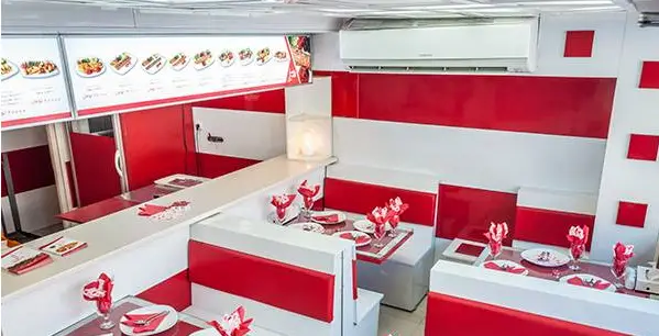 فضای داخلی رستوران خانه کباب ملل با دکوراسیون مدرن قرمز و سفید، شامل میز و صندلی‌های چیده شده و منوی غذایی متنوع.