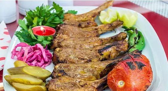 سینی کباب شیشلیک معروف خانه کباب ملل، شامل دنده‌های آبدار، گوجه و فلفل کبابی، سبزیجات تازه و انواع ترشیجات.