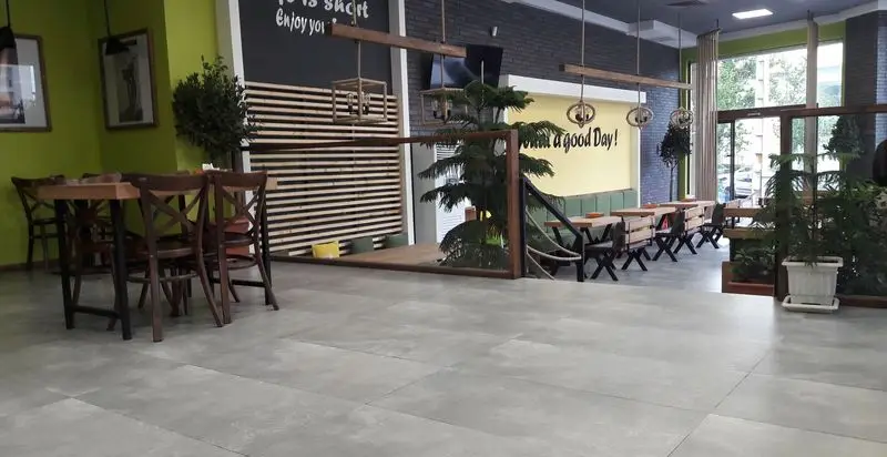 نمای داخلی فست فود اَگِر با دکوراسیون مدرن، میز و صندلی‌های چوبی و گیاهان طبیعی، فضایی دلنشین برای مشتریان فراهم آورده است.