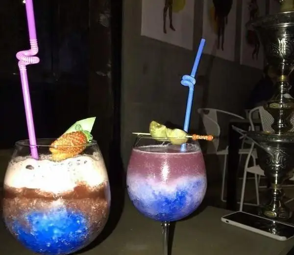 دو نوشیدنی خنک و لایه‌لایه رنگارنگ، شامل اسموتی میوه‌ای و شیک شکلاتی، با تزئینات جذاب در کافی شاپ بلومارلین.