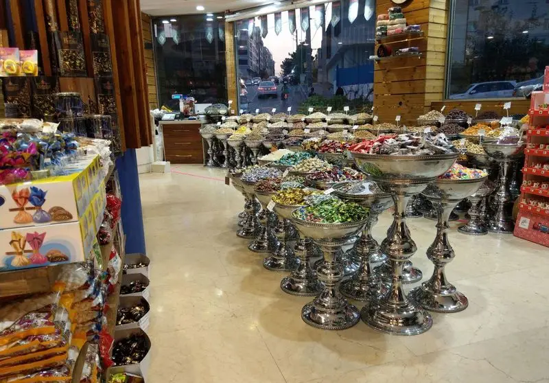 فروشگاه لوکس شیرینی و آجیل آرامیس با تنوع بی‌نظیری از شکلات، خشکبار، مغز و آجیل در ظروف نقره‌ای زیبا و چشم‌نواز.