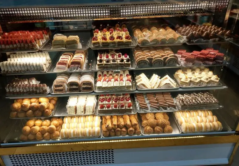 ویترین شیک و پربار شیرینی و آجیل آرامیس با چیدمان هنرمندانه انواع کیک، دسر و شیرینی‌جات لذیذ و تازه آماده عرضه