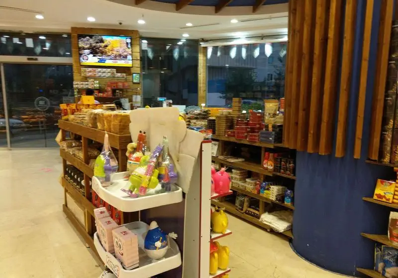 فروشگاه شیرینی و آجیل آرامیس، نمای داخلی با قفسه‌های چوبی پر از شیرینی تازه، آجیل و محصولات متنوع در محیطی روشن و دلپذیر.