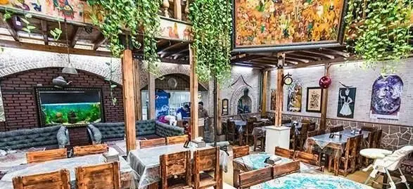 سفره خانه سنتی باغچه: فضایی دلنشین و اصیل ایرانی با دکوراسیون چوبی، گیاهان آویز، نقاشی‌های دیواری و آکواریوم برای مهمانان.