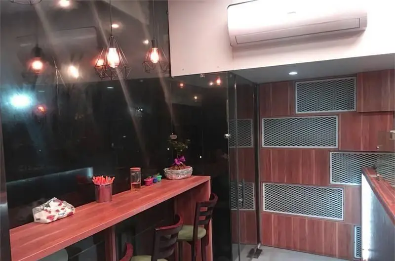 فضای داخلی مدرن و دلپذیر پیتزایی بلا با دکوراسیون شیک، شامل میز بار چوبی، صندلی‌های راحت و نورپردازی گرم. آماده پذیرایی از مشتریان.