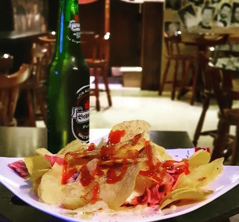 چیپس مخصوص کافه پرستیژ با سس قرمز و نوشیدنی مالت بهنوش در فضای داخلی دلنشین کافه. لذت طعم‌های خاص و محیطی آرامش‌بخش.