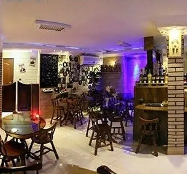 فضای داخلی کافه پرستیژ با چیدمان دنج میز و صندلی‌های چوبی، بار نوشیدنی و دکوراسیون خاص با صفحات وینیل.