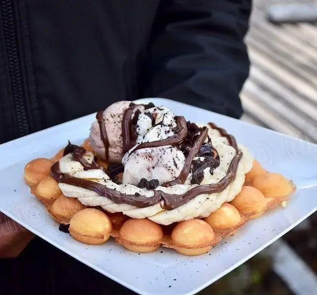 وافل حبابدار طلایی پرشده با بستنی شکلاتی، بستنی اورئو، موز تازه و سس شکلات، دسری دلپذیر از کافه جلاتو متینو.