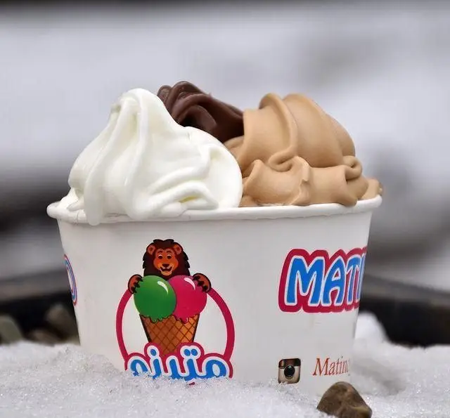 کاپ جلاتو متینو با سه طعم دلپذیر وانیل، شکلات و کارامل، روی برف یا یخ. لوگوی شیر ماتینو روی کاپ بستنی. این جلاتو خوشمزه از کافه جلاتو متینو.