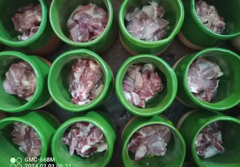 تکه های گوشت تازه و مرغوب در دیزی‌های سفالی سبز، آماده‌سازی برای پخت دیزی اصیل و لذیذ در شاه دیزی پایتخت شعبه یادگار، غذای محبوب ایرانی.