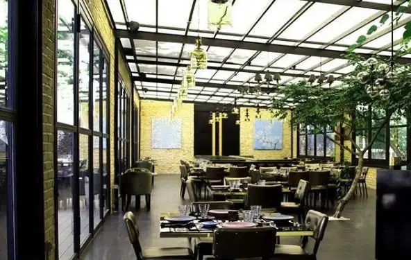 فضای داخلی شیک و مدرن رستوران غذای دریایی سیتادل با سقف شیشه‌ای، درختان سرسبز و میزهای چیده شده برای تجربه غذایی دلنشین.