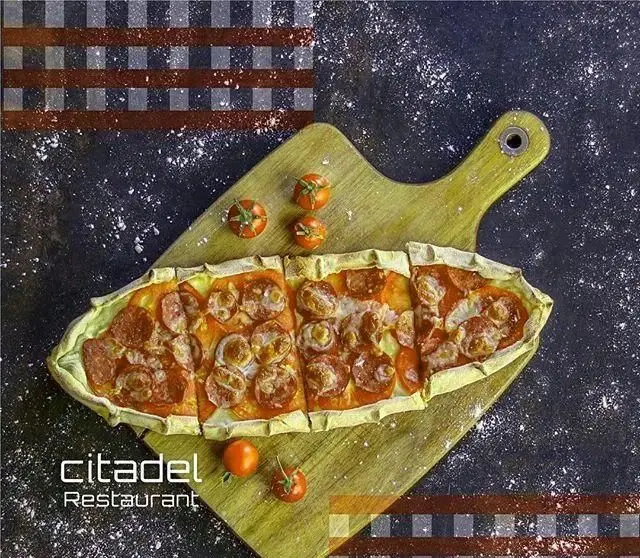 پیده پپرونی و پنیر خوشمزه رستوران سیتادل، غذای دریایی سیتادل، بر روی تخته چوبی با گوجه فرنگی گیلاسی و پس‌زمینه تیره و چهارخانه.