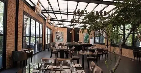 دکوراسیون شیک رستوران غذای دریایی سیتادل، محیطی مدرن با دیوارهای آجری، سقف شیشه‌ای، درخت طبیعی و میزهای آماده برای پذیرایی.