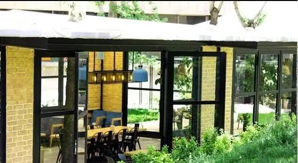 فضای زیبای رستوران غذای دریایی سیتادل با معماری مدرن، پنجره‌های سراسری، درخت داخل سازه، میزهای شیک و نورپردازی دلنشین و فضای سبز.