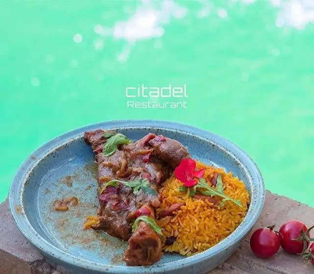 خوراک گوشت لذیذ و پلوی زعفرانی خوشرنگ با تزئین گل در رستوران سیتادل. طعم بی‌نظیر غذاهای تازه از "غذای دریایی سیتادل".